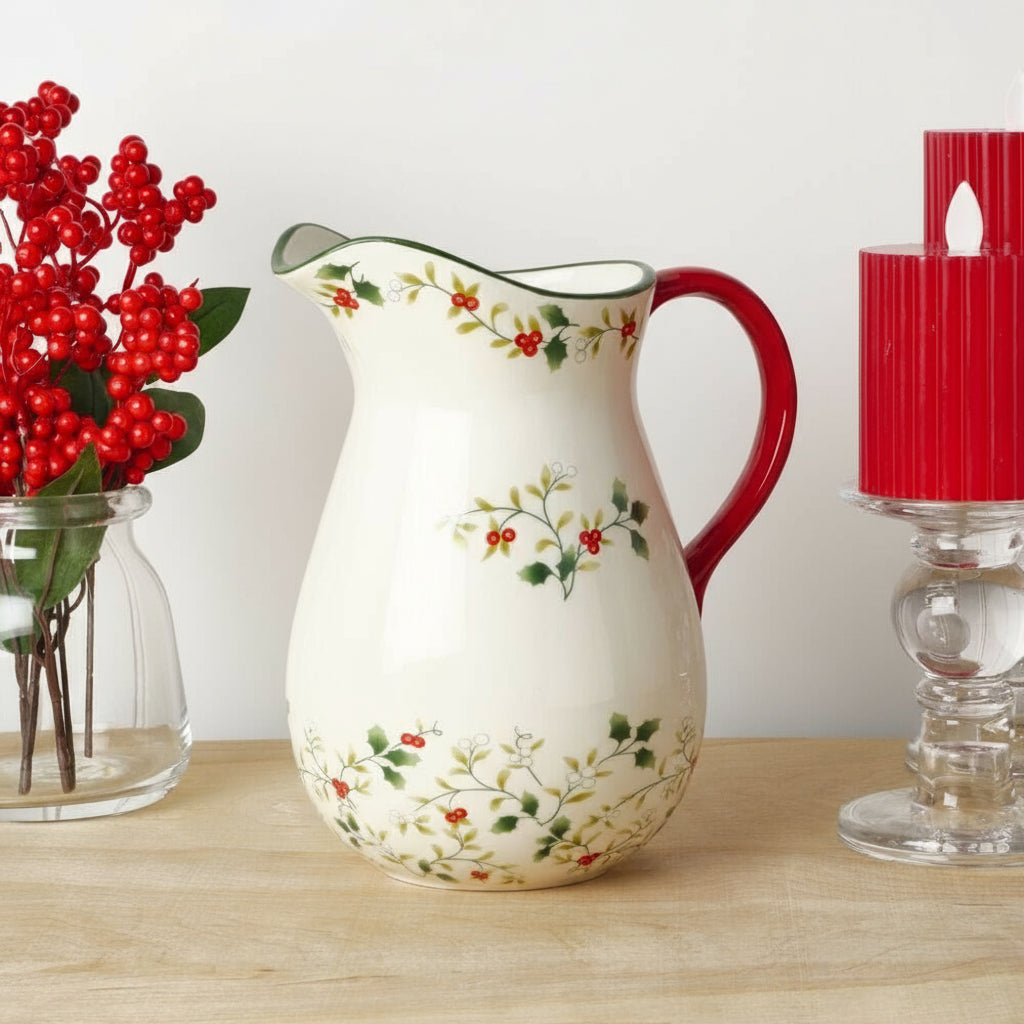 Decorative ceramic pitcher with floral and berry design on a wooden surface.