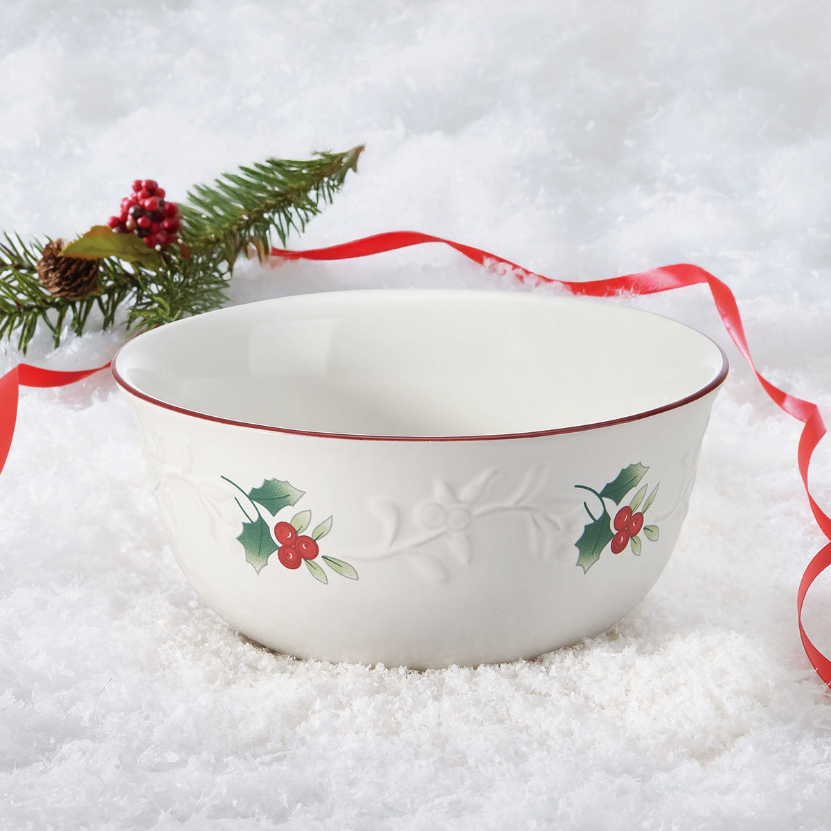 Winterberry Charm Soup Cereal Bowl with red rim and holly berry pattern on snowy background.