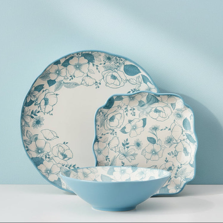 Set of blue floral dinnerware on a wooden shelf with a white tiled wall background.