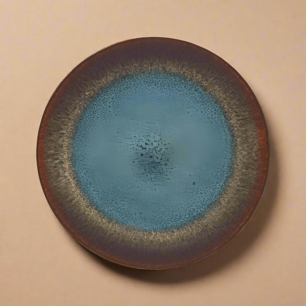 A round, stoneware salad plate with a blue reactive glaze and a visible brand imprint.