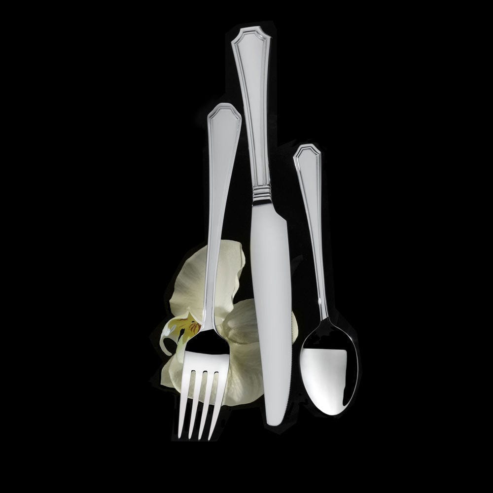Polished flatware with white handle accents arranged around a pale orchid on black background