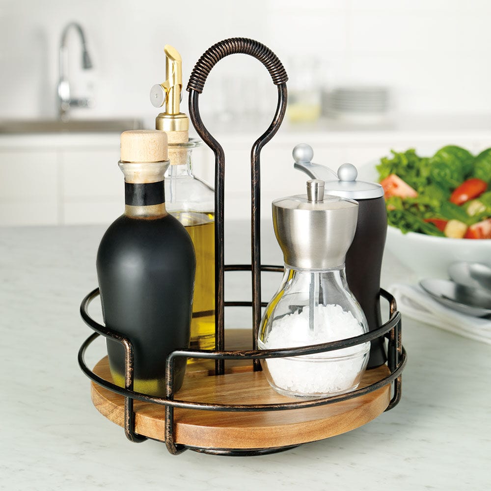 Oval rotating condiment caddy with wooden base and dark metal frame holding oil, vinegar, salt, and pepper